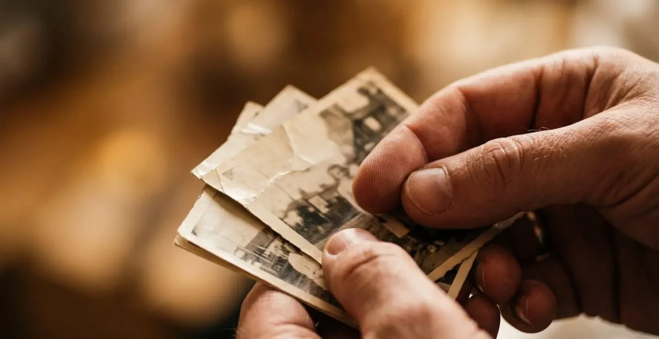 Gros plan sur des mains tenant des photographies personnelles anciennes pour reconstituer la mémoire des objets disparus
